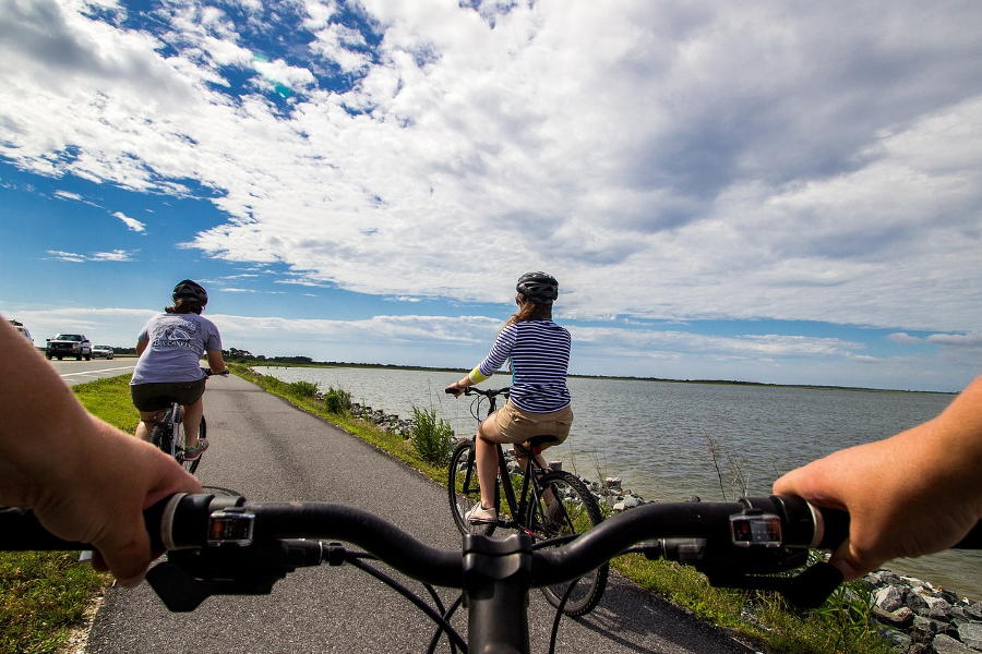 Drei Radfahrer auf einem Radweg an einem See